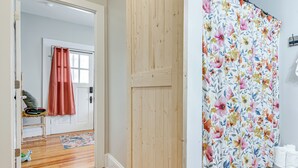 A hallway with wooden flooring, a door with a pink curtain, and a wall with a floral curtain. - 3 Mi to Downtown Covington: Cozy Getaway w/ Porch! (Porterdale)