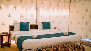 Un lit double avec une literie blanche et turquoise, une tête de lit en bois et un pouf à motifs.