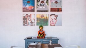 Un coin repas avec une table en bois, deux chaises blanches, un buffet bleu et une statue de Bouddha.