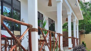 A covered outdoor area with a white structure, wooden railings, and various plants. - Yasa Boutique Hotel (Nungwi)