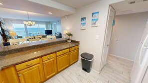 A kitchen with granite countertops, wooden cabinets, and a view of the ocean.