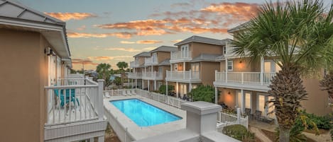 A residential complex with a swimming pool, balconies, and a landscaped garden.