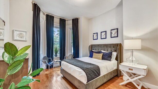 A bedroom with a large bed, a bedside table with a lamp, and a view of the outdoors through the window. - Clean contemporary escape (Boston)