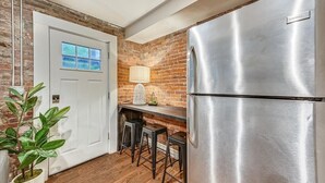 A kitchen with a stainless steel refrigerator, a brick wall, a white door, and a plant. - Clean contemporary escape (Boston)