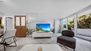 Un saló modern amb televisió de pantalla plana, un sofà, una taula baixa i una zona de menjador.