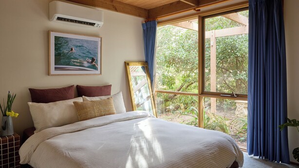 A bedroom with a large bed, a framed picture on the wall, and a window with curtains.