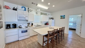 Una cocina moderna con armarios blancos, una isla central y suelo de madera.