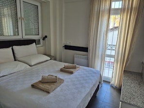 A hotel room with two beds, a window with blinds, a radiator, and a view of the outside. - Vacation apartment in the heart of Fethiye  (Fethiye)