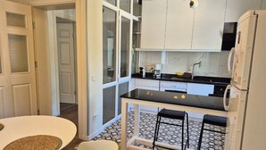 A compact kitchen with a dining area, a refrigerator, and a microwave.