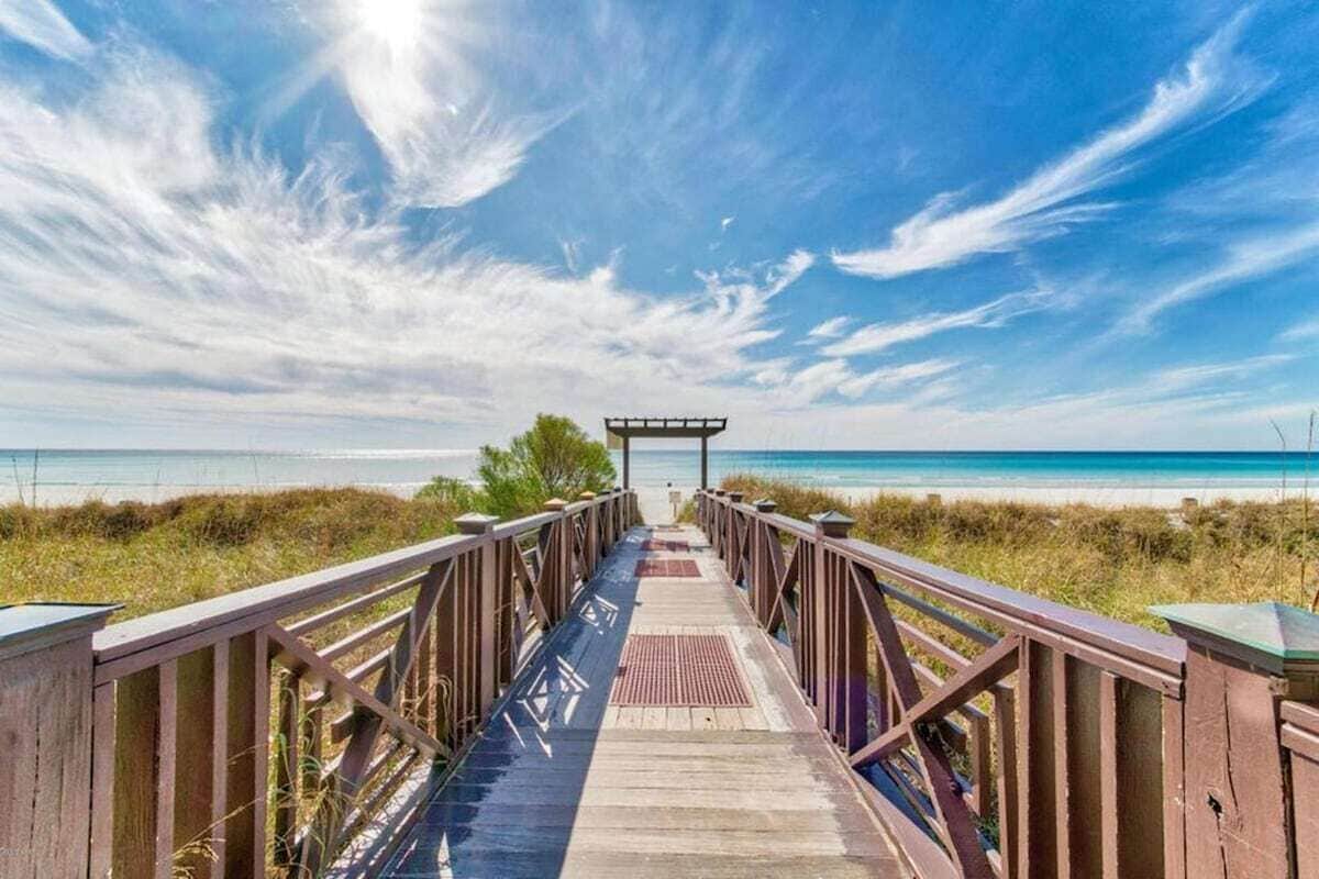 Une promenade en bois menant à une plage, avec un kiosque à l’extrémité.