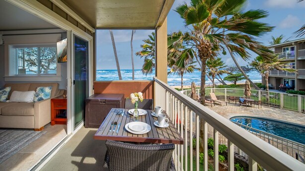A balcony with a table, chairs, and a view of the ocean. - Kailani #213, Oceanfront, Sunrise and Moon Rise Views! (Kapaa)