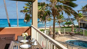 A balcony with a view of the ocean, palm trees, and a pool area. - Kailani #213, Oceanfront, Sunrise and Moon Rise Views! (Kapaa)