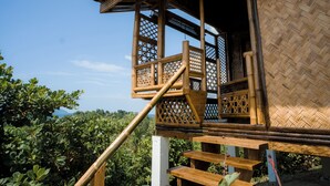 Een houten constructie met een balkon en een trap naar een overdekt gedeelte.