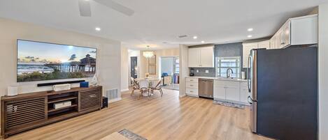 A modern kitchen with white cabinets, a black refrigerator, and a dining area with a wooden table and chairs.
