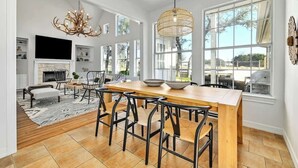 Une cuisine spacieuse avec un grand îlot central, des chaises modernes et un lustre.