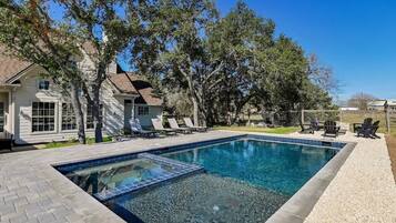 A rectangular swimming pool with clear blue water, surrounded by a pebble-lined deck.