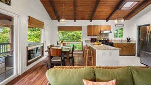 Une cuisine moderne avec des meubles en bois, un îlot central et un coin repas comprenant un canapé vert et des chaises en bois.
