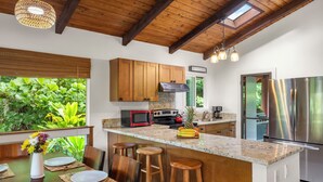 Une cuisine moderne avec des meubles en bois, un réfrigérateur en acier inoxydable et un grand îlot central doté de tabourets de bar.