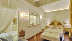 A luxurious bedroom with a large bed, a vanity with a mirror, and a chandelier.