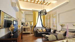 A spacious living room with a large sofa, a dining table set for a meal, and a chandelier.