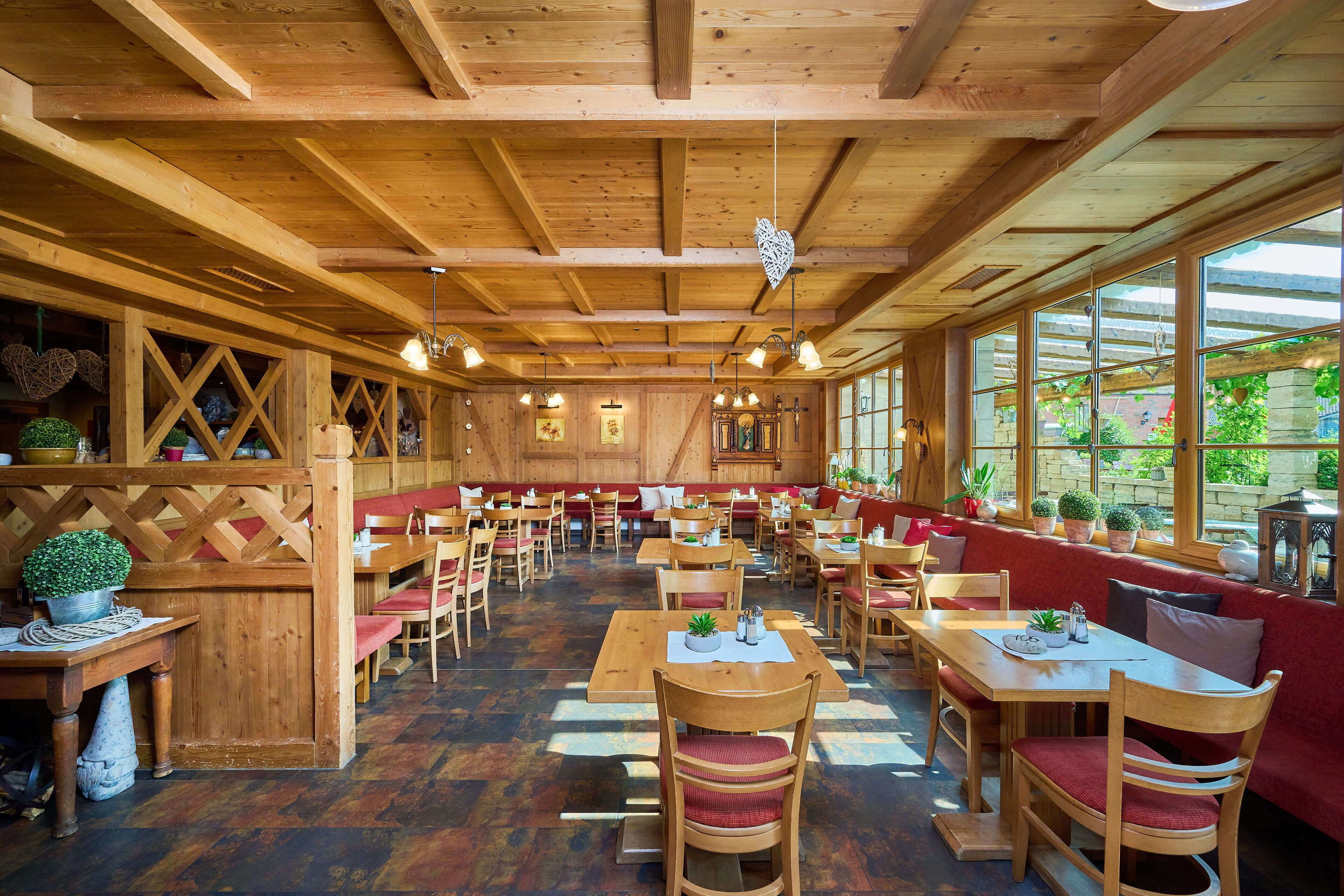 Ein geräumiges Restaurant mit Holzvertäfelungen, mehreren Sitzbereichen und großen Fenstern, die viel Tageslicht hereinlassen.