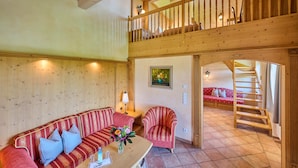 Un vaste espace de vie comprenant un escalier en bois, un ensemble de canapés et une table à manger.