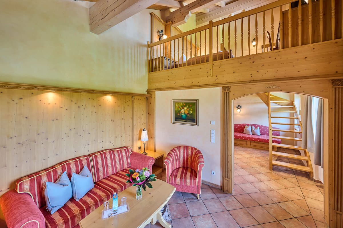 Un vaste espace de vie comprenant un escalier en bois, un ensemble de canapés et une table à manger.