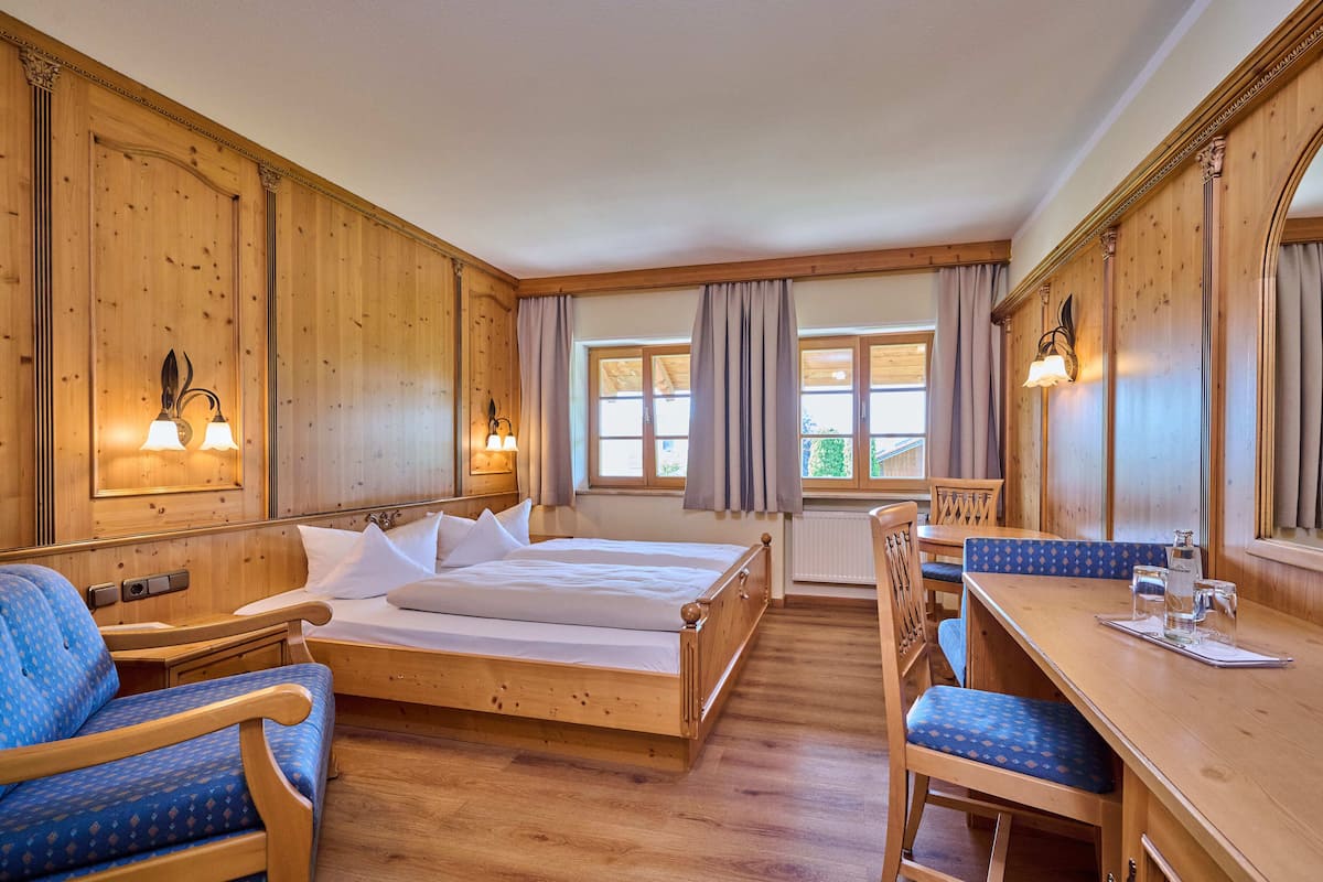 Une pièce en bois avec un lit, deux chaises, une table et une fenêtre avec des rideaux.
