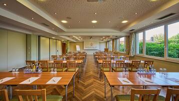 A conference room with multiple tables and chairs, a projector screen, and a banner with the text "HAPPINGER".
