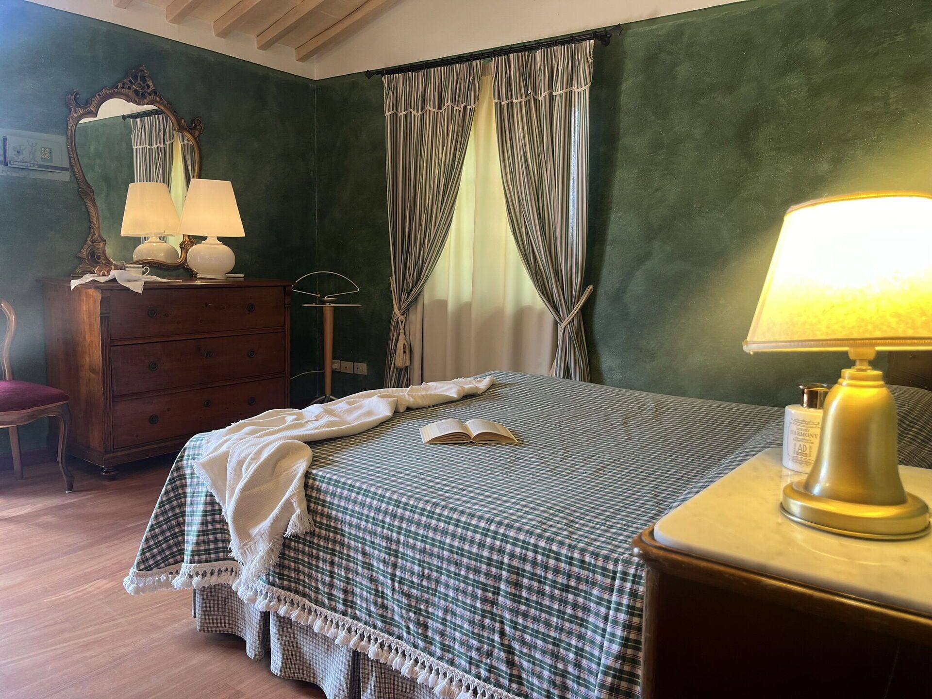 Une chambre à coucher avec une couvre-lit à carreaux, une lampe de chevet, une commode et un miroir.