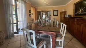 A dining room with a large wooden table, white chairs, and a chandelier. - Villa with Pool and Gym (Diaccialone)