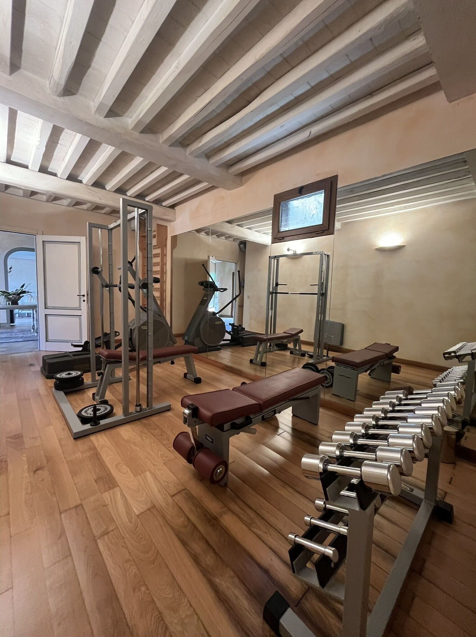 Ein Fitnessstudio mit verschiedenen Trainingsgeräten, darunter Laufbänder, Kraftgeräte und Kurzhanteln.