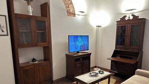 A living room with a television, wooden cabinets, a sofa, and a coffee table. - Il nido dell'Upupa (Montepulciano)