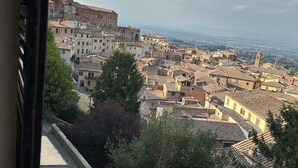 A view of a historic town with medieval architecture, including a prominent tower and a fortified wall. - Il nido dell'Upupa (Montepulciano)