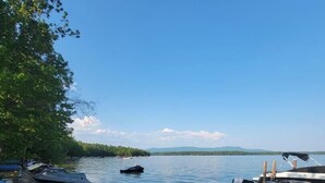 A lakeside dock with boats and a sandy beach. - Lake Breeze Hideaway | Lake Winnipesaukee Vacation Home in Patrician Shores (Meredith)