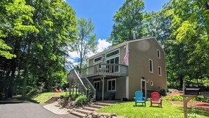 A two-story house with a deck, a mailbox, and outdoor seating. - Lake Breeze Hideaway | Lake Winnipesaukee Vacation Home in Patrician Shores (Meredith)
