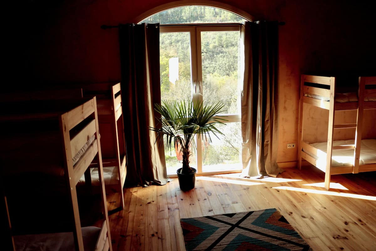 Une pièce avec un plancher en bois, une plante en pot et une fenêtre avec des rideaux.