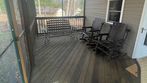 A covered porch with a wooden floor, two Adirondack chairs, and a small table. - Poland Hill Hideaway, located in the beautiful woods surrounding Tionesta, PA (Tionesta)