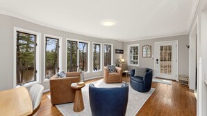 A spacious living room with large windows, a fireplace, and a cozy seating area. - Charming Riverview Cottage Home in Black River Falls (Black River Falls)