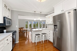 A modern kitchen with white cabinetry, stainless steel appliances, and a wooden floor. - Charming Riverview Cottage Home in Black River Falls (Black River Falls)