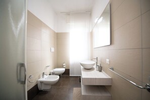 A modern bathroom with a bidet, toilet, and sink.