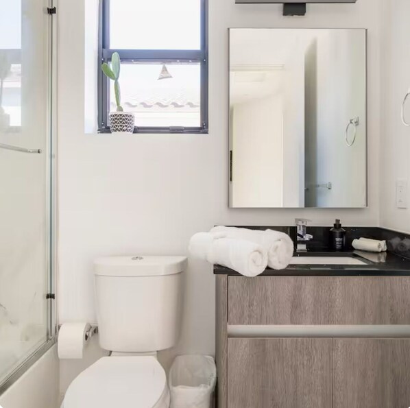 A modern bathroom with a toilet, sink, and a mirror above the sink.