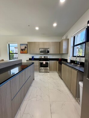 Una cocina moderna con una isla central, electrodomésticos de acero inoxidable y muebles de madera.