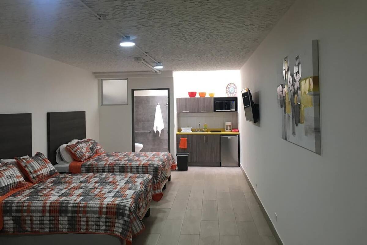Une chambre avec deux lits, un coin cuisine et une salle de bain.