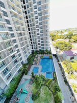 A high-rise residential building with multiple balconies, a rooftop pool area, and a landscaped garden.