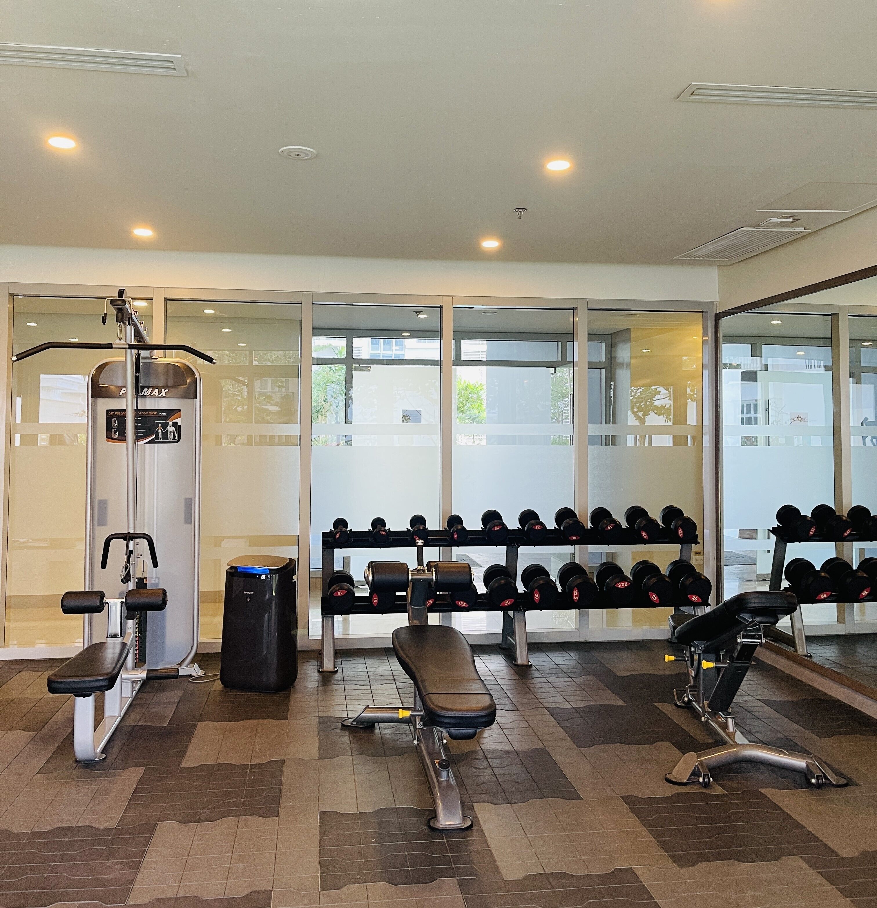 A gym with exercise equipment, a bench, and a rack of dumbbells.