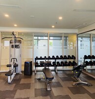 A gym with exercise equipment, a bench, and a rack of dumbbells.