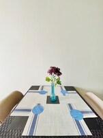 A table with a blue vase containing flowers, set on a patterned tablecloth.