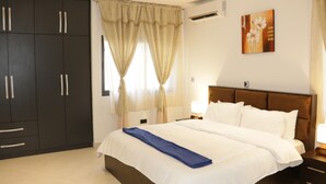 Une chambre d’hôtel avec un grand lit, une armoire, une table de chevet avec une lampe et un tableau au mur.