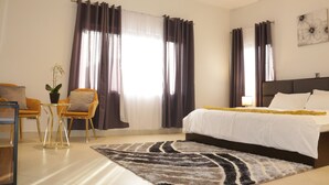 Une chambre d’hôtel avec un lit, un canapé, une petite table et des rideaux.